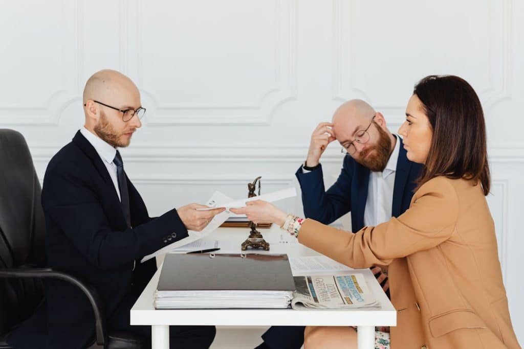 Legal consultation with a client handing case documents to a lawyer during a formal meeting